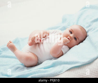 Baby crampiformi piede con una mano, mentre il pugno la messa in bocca con gli altri Foto Stock