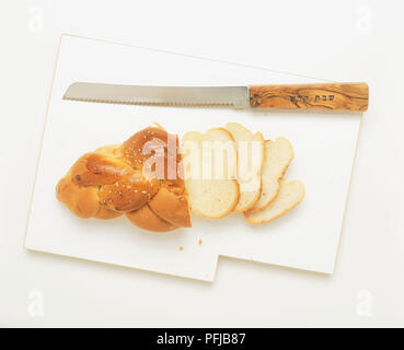 Parzialmente in forma di pane a fette di pane challah con speciale sabato il coltello sul tagliere, vista da sopra Foto Stock
