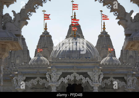 Gran Bretagna, Inghilterra, Londra, Neasden, BAPS Shri Swaminarayan Mandir, marmo bianco tempio indù, a cupola con dettagli rosso e bandiere bianche Foto Stock