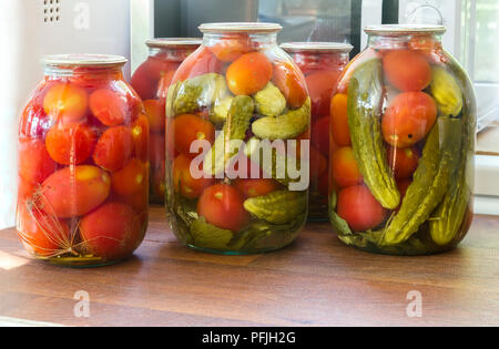 Conserve di pomodori e cetrioli in grandi vasi di vetro. Foto Stock
