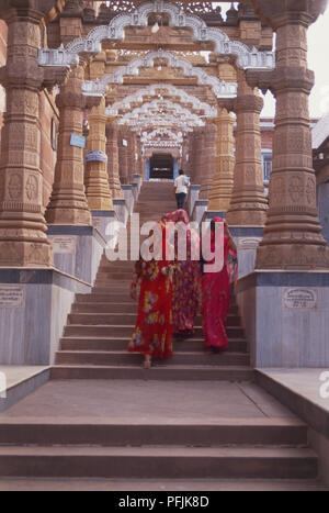 India Rajasthan, Osian, Sachiya Mata Temple, donne in variopinti abiti tradizionali a piedi fino a montante di gradini rivestiti che conduce al tempio ingresso, vista posteriore. Foto Stock