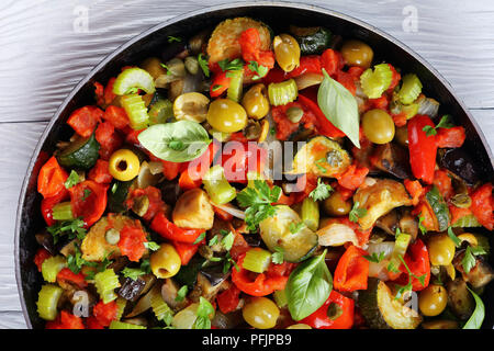 Verdure fritte, le olive verdi, capperi, il sedano e le erbe in una padella, vista da sopra, close-up Foto Stock