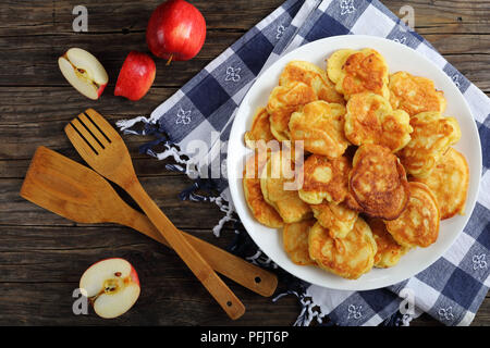 Deliziosa Mela Yogurt Greco frittelle - spessi, morbidi e caricato con juicy pezzi di frutta, sulla piastra bianca sul vecchio dark tavolo in legno con spatole un Foto Stock