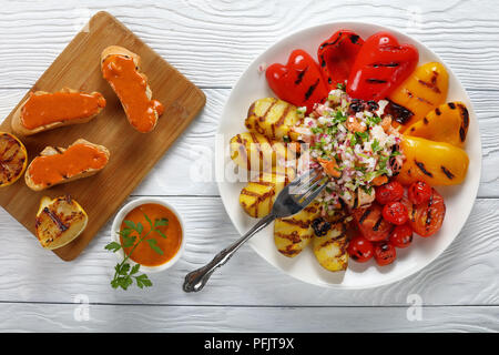 Deliziosa insalata di gamberetti, polpi, calamari cozze servita con verdure grigliate sulla piastra bianca sul tavolo di legno. toast con la paprika la maionese o Foto Stock
