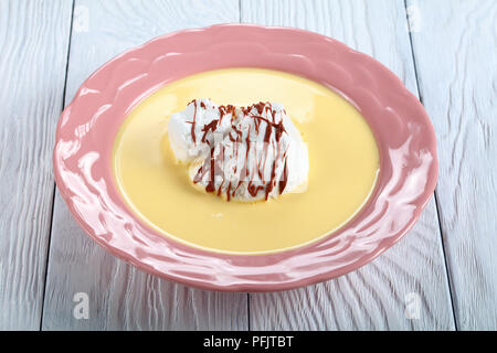 Un'isola galleggiante dessert o uccelli latte, consistente di meringa su Flottante Italienne color crema e spruzzata con glassa al cioccolato in una piastra di rosa su woo Foto Stock