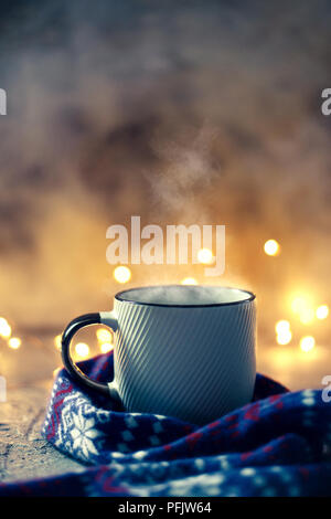 Inverno tazza da caffè coperto con lana sciarpa su luci bokeh di fondo Foto Stock