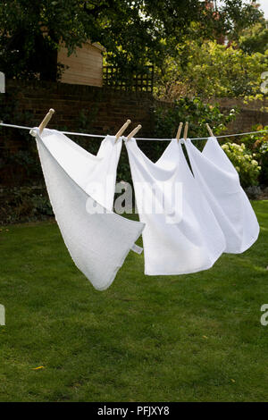 Tre asciugamani bianchi essiccazione su una linea di lavaggio Foto Stock