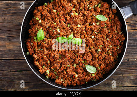 Close-up di hot succosa carne macinata di manzo stufato con salsa di pomodoro, spezie, basilico tritato finemente le verdure e il sedano in padella, autentica ricetta, horizont Foto Stock