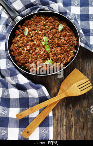 Delizioso ragù bolognese - ingrediente principale per la pasta o le lasagne in padella sul tavolo di legno, verticale vista da sopra Foto Stock