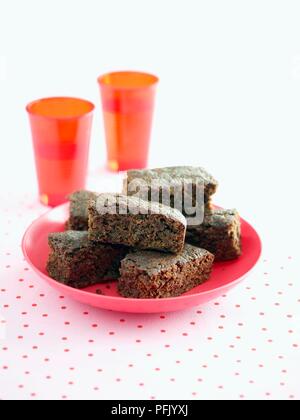 Lo zenzero e zucca torte su piastra di colore rosa, con due red bicchieri di plastica nelle vicinanze Foto Stock