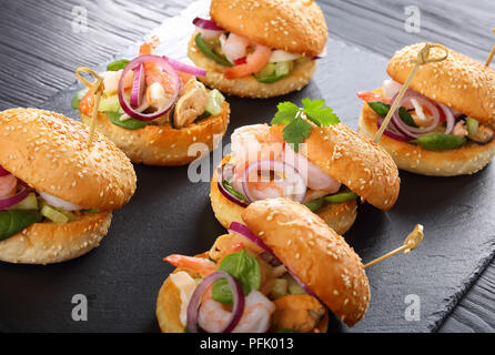 Deliziosi hamburger grigliati segnato con gli spiedini di bambù o pinchos con frutti di mare, verdure e verdi su nero ardesia vassoio, Spagna cucina, close-up, vista Foto Stock