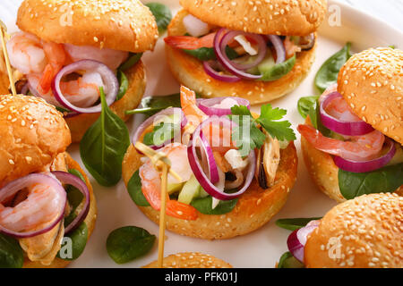 Deliziose grigliate hamburger succosa segnato con gli spiedini di bambù o pinchos con frutti di mare - Gamberetti, cozze, strisce di calamari, cipolla rossa e spinaci su bianco di Foto Stock