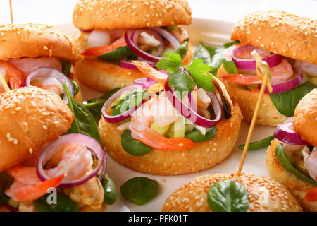 Grigliate gli hamburger succosa segnato con gli spiedini di bambù o pinchos con frutti di mare - Gamberetti, cozze, strisce di calamari, cipolla rossa e gli spinaci sul piatto bianco, Spagna Foto Stock