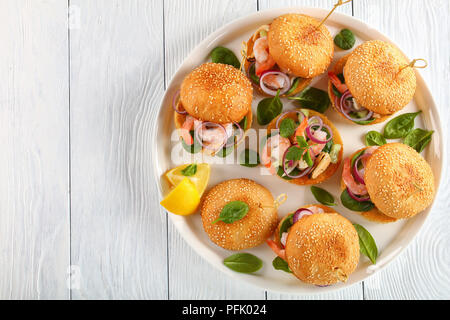 Grigliate gli hamburger succosa segnato con gli spiedini di bambù o pinchos con frutti di mare - Gamberetti, cozze, strisce di calamari, cipolla rossa e gli spinaci sul piatto bianco con le Foto Stock