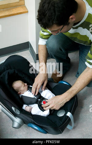 L'uomo reggetta nel neonato nella culla portatile, close-up Foto Stock