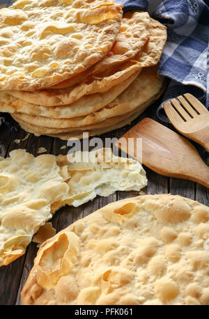 Close-up di facile in casa senza lievito croccante di pasta sfoglia vegan focacce di grano sul tavolo di legno con carta asciugatutto e spatole, ricetta semplice, vertica Foto Stock