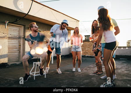 Gruppo di amici felice avente parte sul tetto Foto Stock