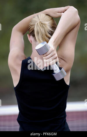Giocatore di Tennis tenendo il manubrio dietro la schiena, vista posteriore Foto Stock