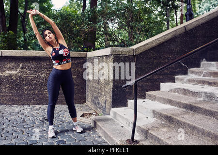 Latina donna ispanica si estende prima di un allenamento Foto Stock