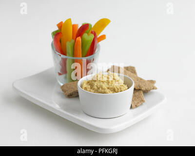 Ciotola di hummus, bastoncini di peperoni, la carota e il sedano in vetro, con pane pitta sul vassoio Foto Stock