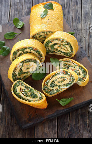 Uova e formaggio involtino servita sotto forma di un rotolo realizzato a partire da un pezzo piatto di spugna salati, diffondere con un morbido ripieno di spinaci, formaggio feta e carote Foto Stock