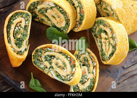 Involtino di uovo servite sotto forma di un rotolo realizzato a partire da un pezzo piatto di spugna salati, diffondere con un morbido ripieno di spinaci, formaggio feta e carote e laminati Foto Stock
