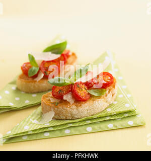 Bruschetta di pomodoro con scaglie di parmigiano e le foglie di basilico, close-up Foto Stock