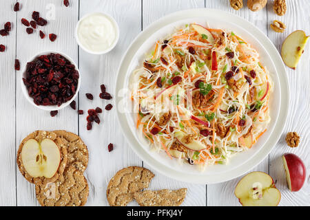 Close-up di Apple di mirtillo palustre e noci insalata Coleslaw su una piastra bianca sul tavolo di legno con mela rossa multigrain, fette biscottate e yogurt greco dressi Foto Stock