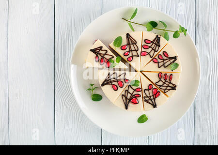 Deliziosa allestita cheesecake tagliare a fette con fresco menta verde su bianco piatto sul tavolo di legno, vista da sopra, uno spazio vuoto per il testo le Foto Stock