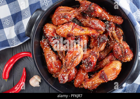 Deliziose grigliate di pollo teriyaki bacchette cosparso con semi di sesamo nero braciere sul tavolo di legno con carta asciugatutto, vista orizzontale da ab Foto Stock