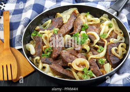 Close-up di deliziosi piatti di carne di vitello pezzi di fegato saltate in padella e stufati con anelli di cipolla in una padella Foto Stock