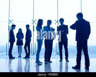 Sagome dei popoli asiatici in piedi discutere di affari in ufficio moderno. Foto Stock
