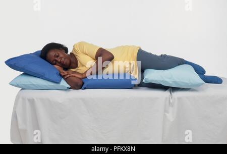 Donna incinta che giace sul lato supportato da cuscini Foto Stock