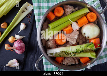 Ingredienti per spezzatino di vitello o blanquette di vitello - pezzi di sbollentati carne di vitello in stock remouillage in casseruola con bouquet garni, cipolla pique e Foto Stock