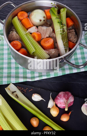 Ingredienti per spezzatino di vitello o blanquette di vitello - pezzi di sbollentati carne di vitello in stock remouillage in casseruola con bouquet garni, cipolla pique e Foto Stock