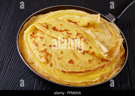 Appena fritte calde crepes francese su una padella su tavoli in legno nero, vista da sopra, close-up Foto Stock