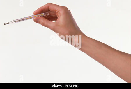 Donna di mano che tiene un termometro, close-up Foto Stock