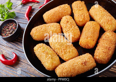 Close-up di deliziose spagnolo fritte crocchette di patate, croquetas su una padella su una tavola in legno rustico, orizzontale vista da sopra Foto Stock