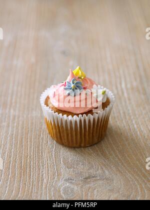Spugna Cup cake con glassa di rosa e fiori di glassa sulla parte superiore Foto Stock