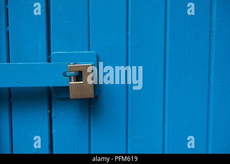 In legno di colore blu porte bloccate con un moderno blocco giallo Foto Stock