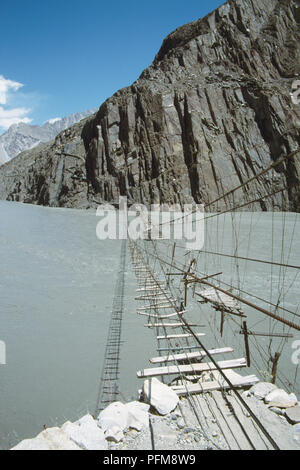 Legno, non particolarmente sicuro cercando in legno ponte di sospensione, in cattive condizioni, oltre il Fiume Hunza. Foto Stock