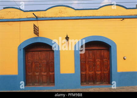 Messico, San Cristobal de las Casas, arancio e blu facciata di un inizio di casa coloniale con pesanti porte di legno e un tetto piatto. Foto Stock