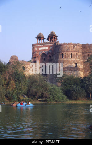 India, Delhi, Purana Qila, il che significa che il vecchio Fort, antica fortezza in piedi su un antico tumulo, solidi muri in pietra arenaria, due Chhatri con tilework decorativo, pareti arrotondate con piccole finestre, gite in barca sul lago in primo piano. Foto Stock