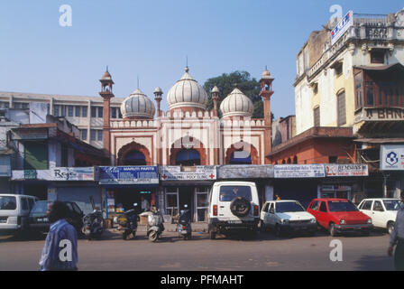 India, Delhi, Fakr-ul-Masjid, pietra arenaria rossa moschea, white cupole e minareti con strisce nere, sollevandosi al di sopra di file di negozi e uffici lungo la strada trafficata, automobili e moto parcheggiata di fronte. Foto Stock