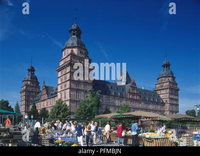 In Germania, in Baviera, Aschaffenburg, la pietra arenaria rossa esterno di Schloss Johannisburg, con persone di shopping presso l aria aperta mercato di frutta e verdura in prima linea dell'immagine Foto Stock