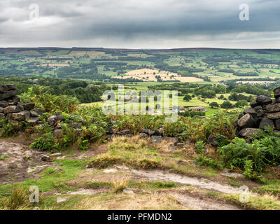 Vista su Wharfedale attraverso uno spazio in un secco parete in pietra vicino posto sulla rupe di Burley Moor West Yorkshire Inghilterra Foto Stock