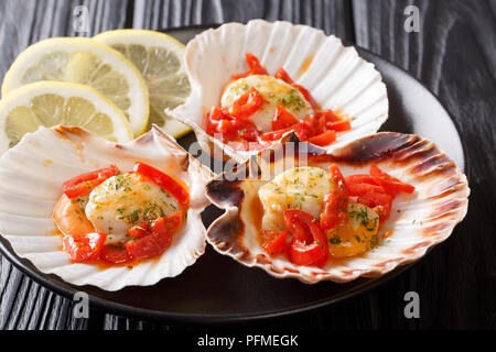 Primo piano di tre di capesante di mare in pomodoro prezzemolo e limone close-up su uno sfondo scuro. Posizione orizzontale Foto Stock