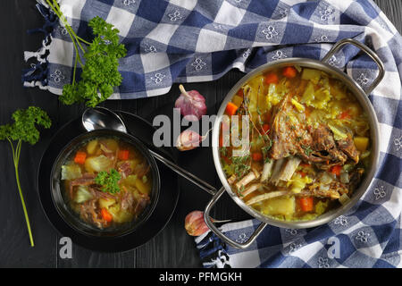 Close-up di deliziose islandese zuppa di agnello con spezie e verdure o kjotsupa in un acciaio inossidabile casseruola pan e nella ciotola sul tavolo di legno con Foto Stock