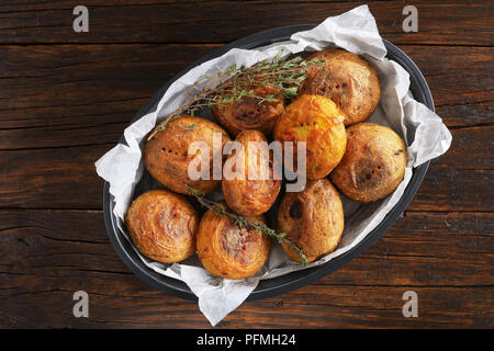 Pane appena sfornato patate intere con il timo in una teglia sul tavolo di legno, vista orizzontale dal di sopra, close-up Foto Stock