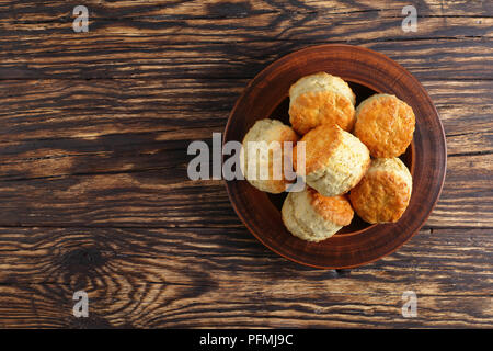 Delizioso pane appena sfornato in casa inglese scones sulla piastra di argilla sul tavolo di legno, vista da sopra, close-up Foto Stock